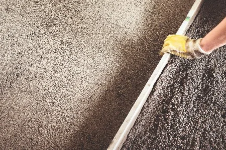Person glättet Beton mit Richtlatte